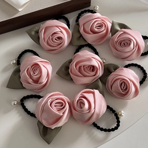 Détail de 8 chouchous roses en soie avec feuilles vertes et un pendentif perle blanche