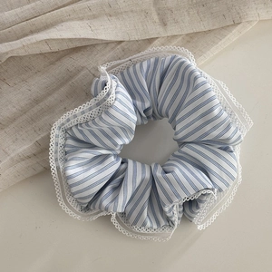 Detail of blue and white striped fabric scrunchie with delicate white lace edges