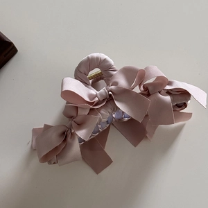 Dettaglio del fermaglio per capelli con fiocco in raso rosa che mostra la trama liscia del nastro