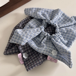 Detailed texture of plaid fabric scrunchies with decorative floral buttons and bow knot