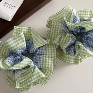 Détail de chouchous à carreaux verts et bleus avec dentelle blanche sur base blanche