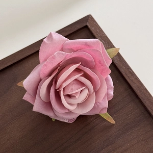 Close-up detail of handcrafted pink fabric rose hair clip with realistic fabric texture