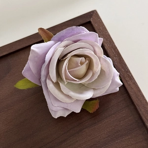 Close-up of a gradient purple fabric rose hair clip with realistic green leaves