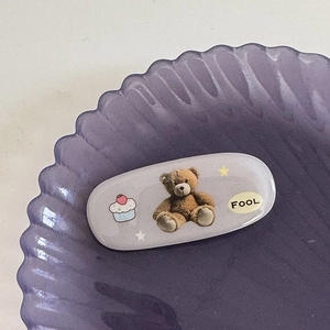Vue macro détaillée d'une jolie pince à cheveux ours sur un plateau coquillage violet