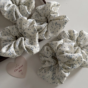Close-up of floral fabric hair scrunchies with elegant pleats and blue flower patterns