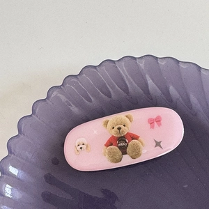 Gros plan d'une pince à cheveux rose avec imprimés d'oursons et chiots sur un plateau
