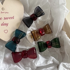 Detailed macro view of handmade resin bow hair clips in five elegant colors on white paper