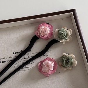 Vintage camellia fabric hair pins set with pink and green flowers on a wooden tray