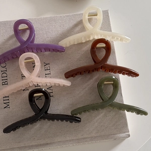 Set of six minimalist matte resin hair claw clips in various elegant colors on a book