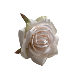 Elegant cream fabric rose hair clip with green leaves on a clean white background