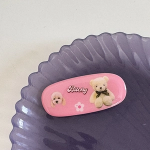 Gros plan d'une pince à cheveux rose avec motifs d'ours sur un plateau décoré