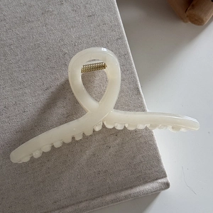 Minimalist cream resin shark hair claw clip detail on aesthetic textured book cover