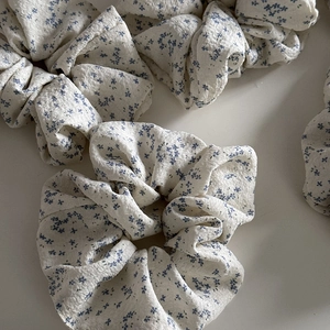 Floral fabric scrunchies with blue flower patterns on a cream background flat lay view