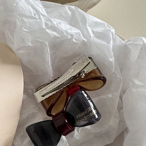 Elegant bow-shaped hair clip in brown and burgundy resin with handmade gold lettering