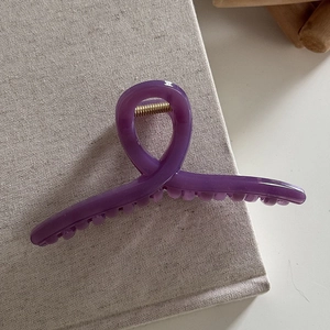 Top view of a purple translucent hair claw clip with golden spring and resin texture