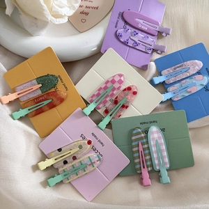 Close-up of glittery fruit series hair clips in pastel colors on satin fabric