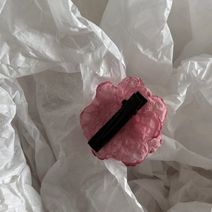 Close-up of pink fabric camellia hair pin with metallic clip on white tissue paper