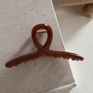 Close-up of minimalist amber hair claw clip with golden metal spring and smooth finish