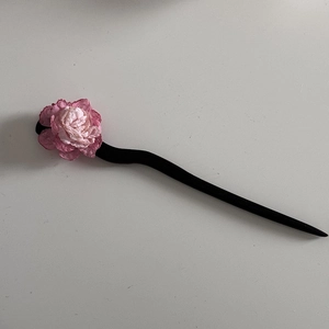 Close-up of pink camellia wooden hair pin with elegant gradient petals and curved black stem