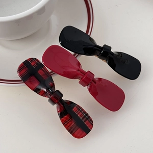Close-up of three acetate bow hair clips in glossy black, red and checkered patterns