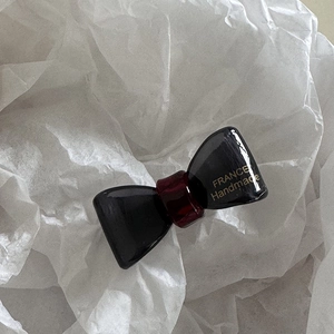 Detailed macro view of black and dark red bow hair clip with FRANCE Handmade gold text