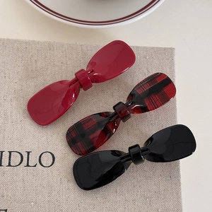 Close-up of three acetate bow hair clips in solid red, black, and plaid patterns