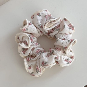 Détail d'un chouchou floral avec fleurs roses sur tissu en maille ajourée