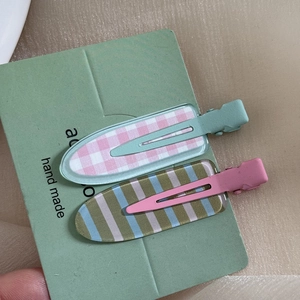 Close-up of pink plaid and striped non-crease hair clips on a handmade card display