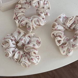 Vue détaillée de trois chouchous en dentelle florale avec motifs roses et volants
