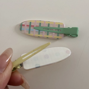 Detail showing the metal duckbill clips and colorful acrylic plates of these hair accessories