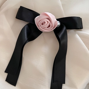 Close-up of elegant black satin bow hair claw with pink rose and pearl detail
