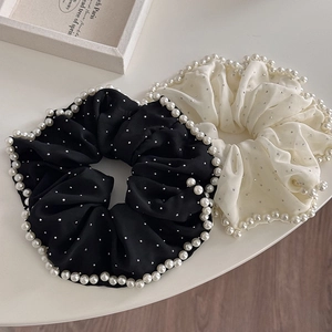 Détail de chouchous noirs et crème surdimensionnés avec perles et strass brillants