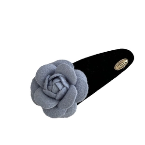 Blaue Samt-Kamellie-Haarklammer mit elegantem Gold-Logo und schwarzer Stoffbasis