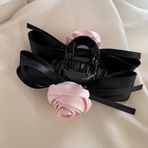 Elegant black ribbon bow hair claw clip with light pink satin roses on beige silk cloth