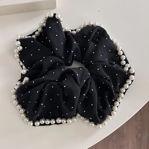 Détail d'un chouchou en mousseline noire avec bordure de perles et paillettes argentées