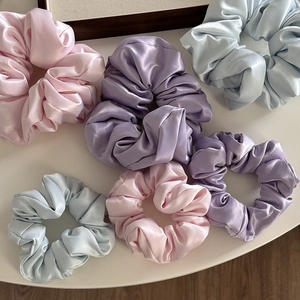 Dettaglio di elastici in raso opaco nei toni pastello rosa, viola e blu effetto seta