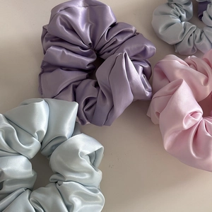 Dettaglio degli elastici scrunchie in raso opaco nei colori pastello lavanda blu e rosa