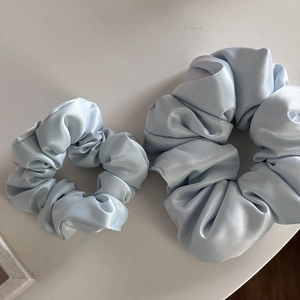Dettaglio di elastici scrunchie in raso celeste in due dimensioni con finitura opaca