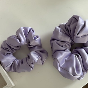 Dettaglio di due elastici scrunchie in raso lavanda di diverse dimensioni e consistenza