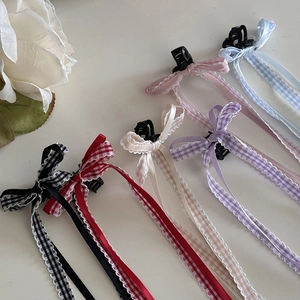 Dettaglio di fermagli per capelli con fiocchi a quadri e lunghi nastri in sei colori vivaci