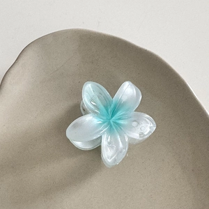 Détail de la pince à cheveux plumeria dégradé bleu et blanc sur support céramique