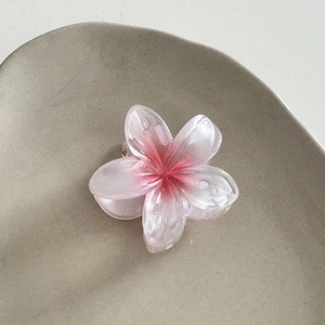Gros plan détaillé de la pince à cheveux fleur dégradé rose et blanc avec gouttes d'eau