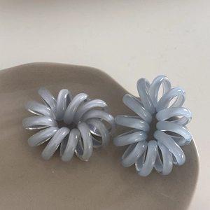 Dettaglio di elastici per capelli a spirale azzurri su un vassoio di ceramica