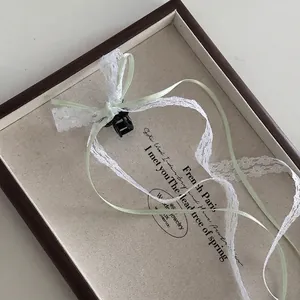 Detail of mini hair claw with white lace and light green ribbon on a wooden tray