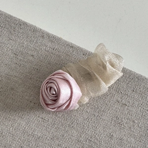 Close-up of pink satin rose hair clip with champagne gold mesh fabric detailing