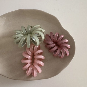 Tre elastici per capelli a spirale in colori pastello su un vassoio di ceramica