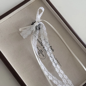 Detailed macro of a white lace bow hair clip with ribbons on a jewelry box background