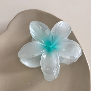 Vue détaillée d'une grande pince à cheveux fleur en résine mate bleu et blanc sur un plateau
