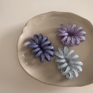 Tre elastici per capelli a spirale viola e blu su un piatto di ceramica decorativo