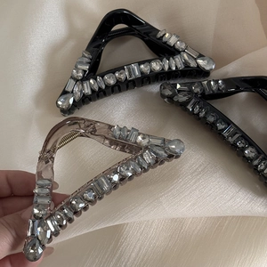 Detail of triangle hair claws with sparkling rhinestones on beige silk fabric
